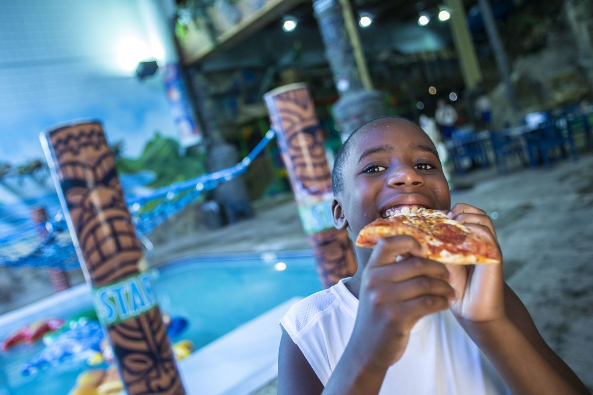 A kid eats pizza at Edgewater Hotel & Waterpark
