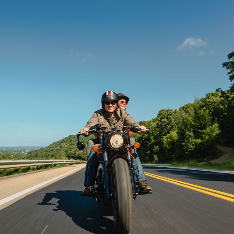 Red wing smiling couple driving motorcycle