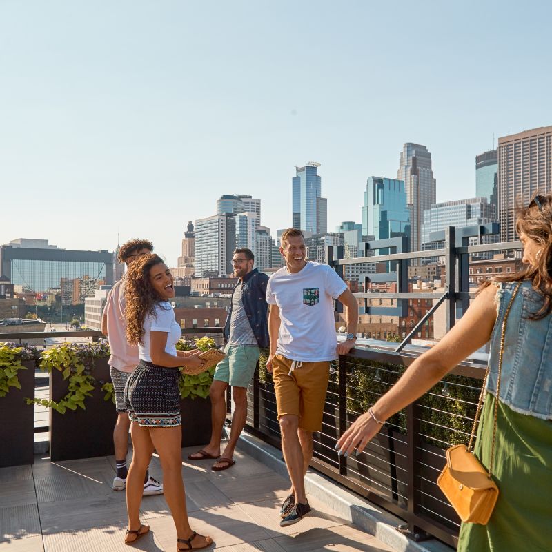 Group of friends on the rooftop of Hewing Hotel overlooking downtown Minneapolis